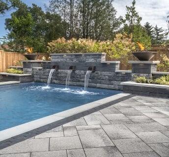 stunning backyard pool setting with bluestone pool surround and cobblestone wall with waterfall feature