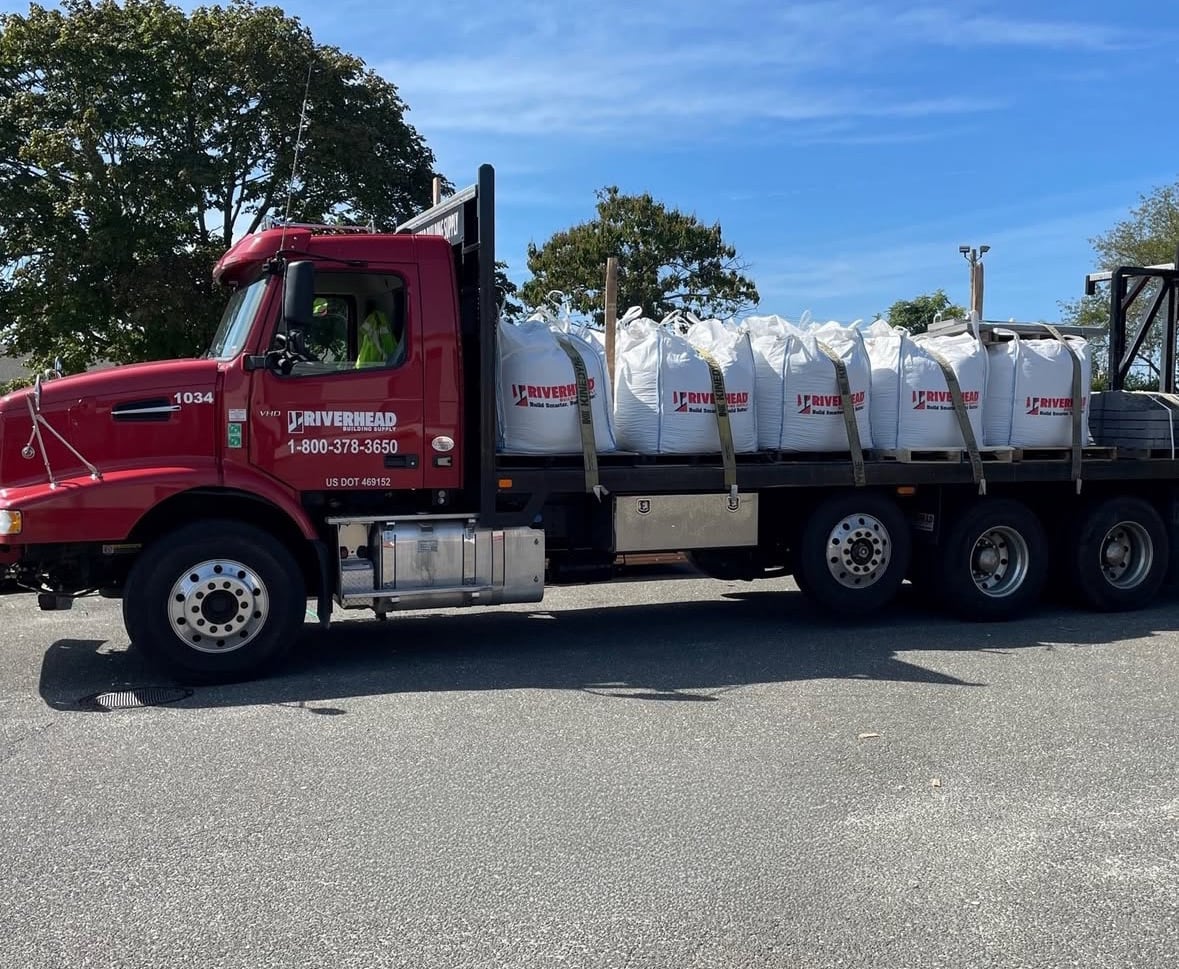 Riverhead Building Supply flatbed truck with bags of aggregate sand and stone for masonry projects