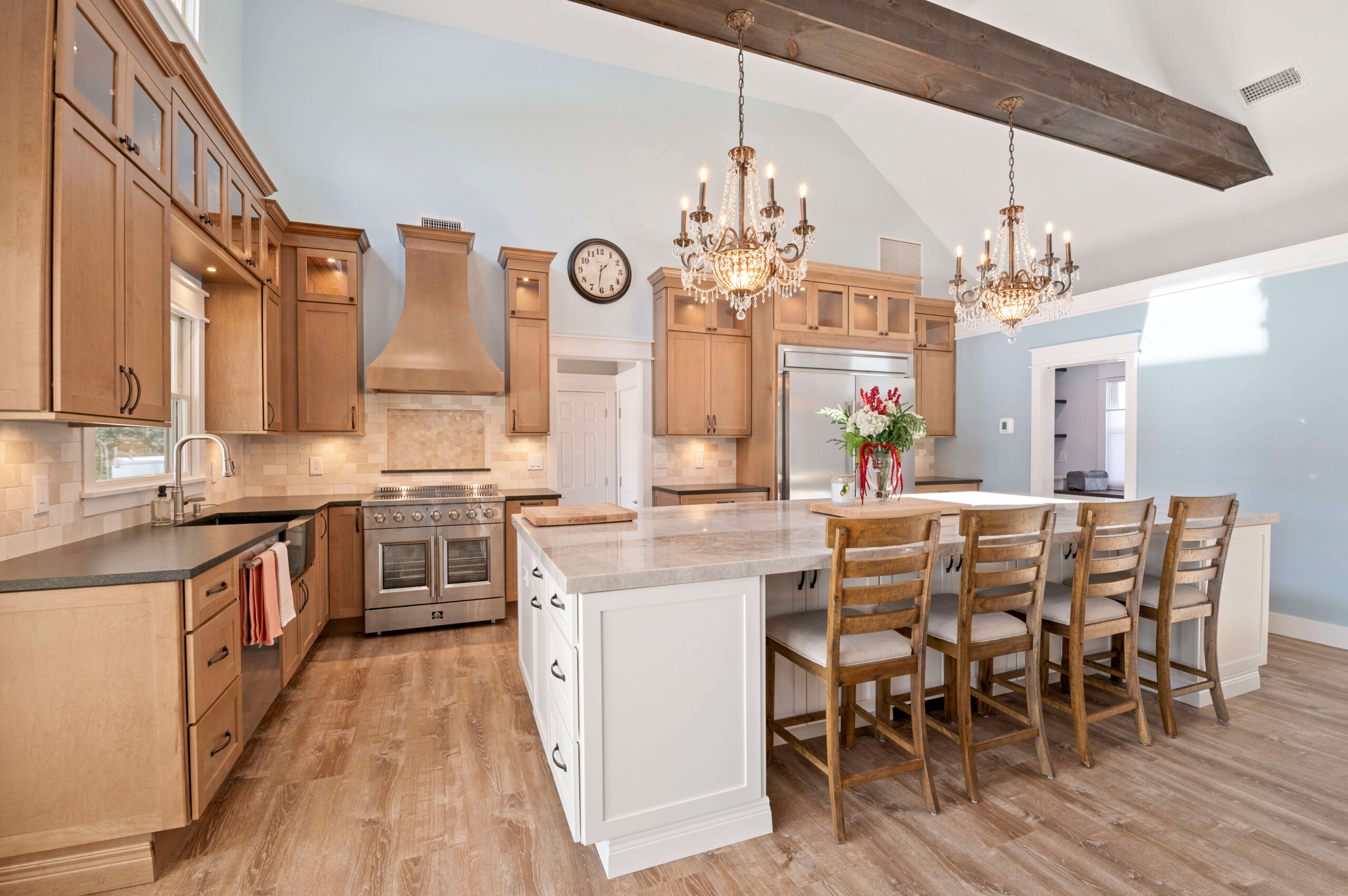 Custom kitchen with White Icing island, Biscotti cabinetry, glass uppers, vaulted ceiling, and built-in storage for seamless design.