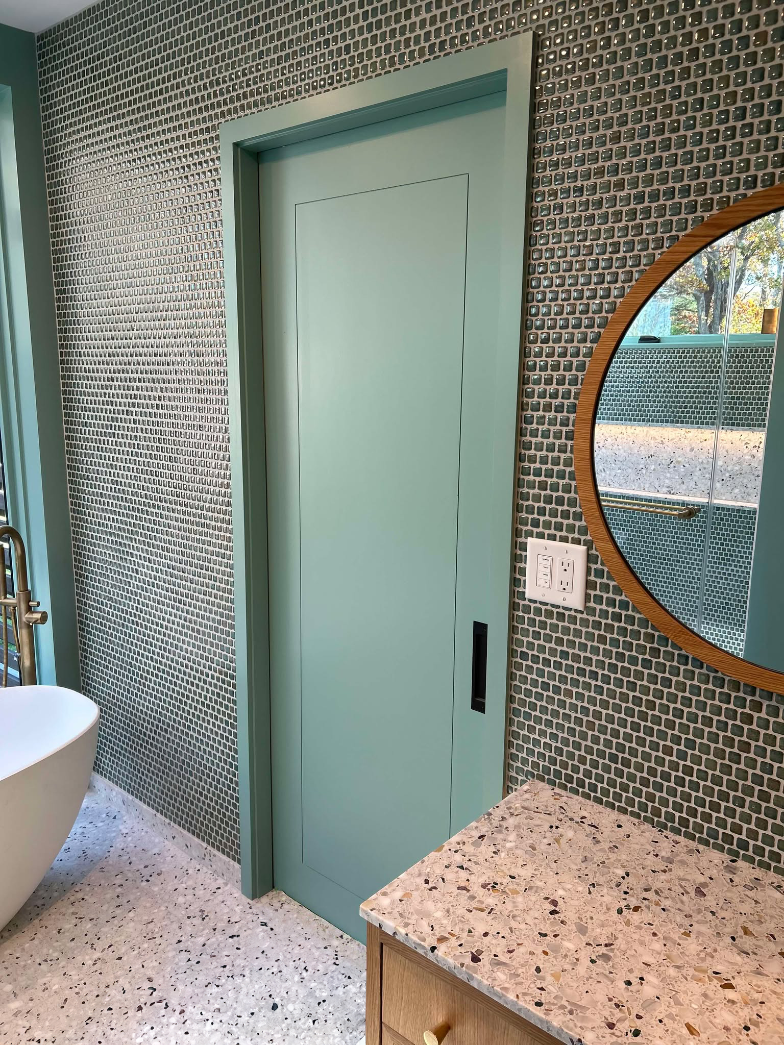 Upstate Door interior door features a space-saving sliding design with clean lines and custom architectural wood craftsmanship in seafoam green